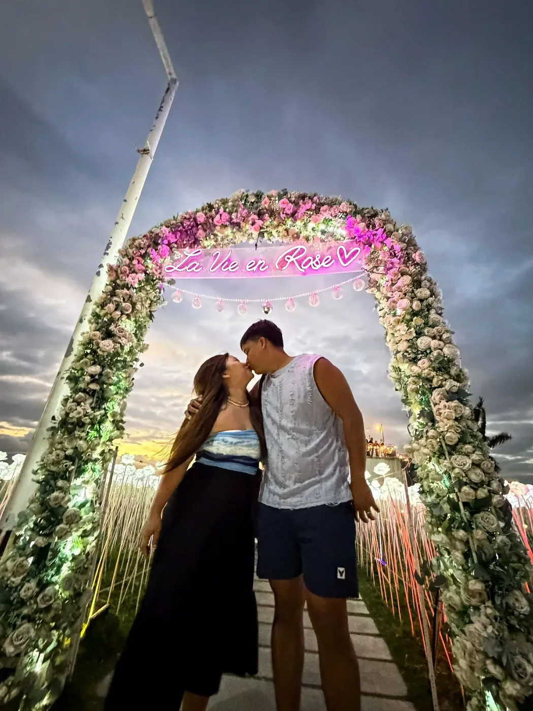 A couple under the La Vie en Rose flower arch
