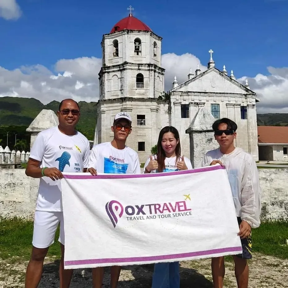 Guests holding a Pox Travel towel in front of Oslob Church