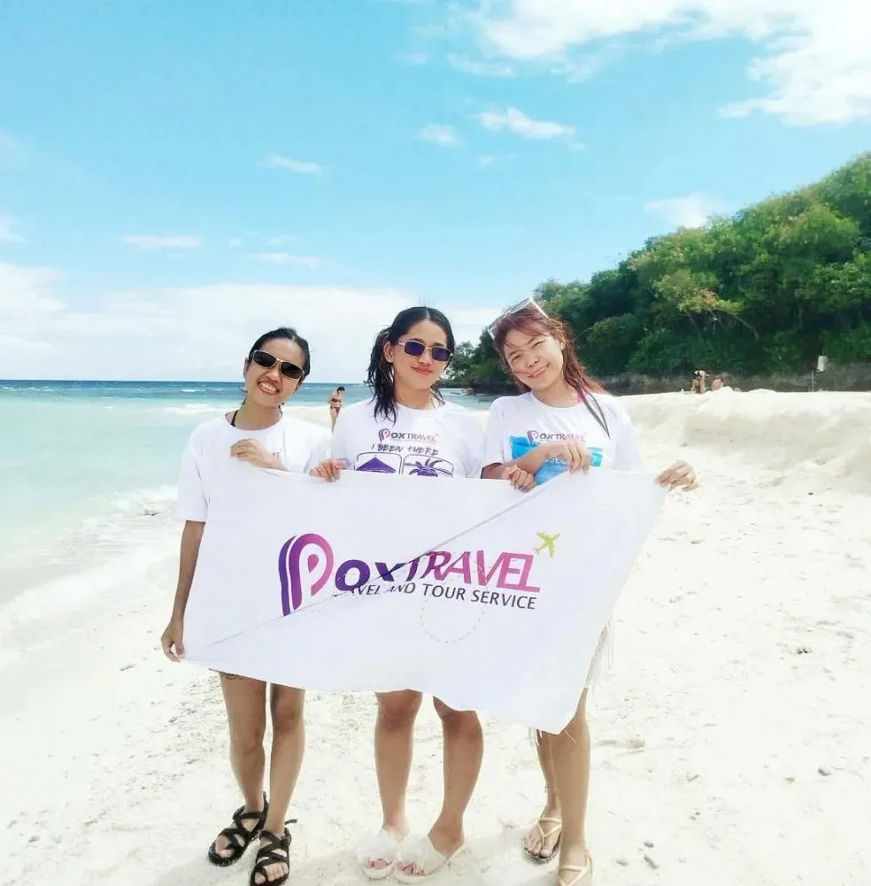Three guests holding a Pox Travel towel on the beach